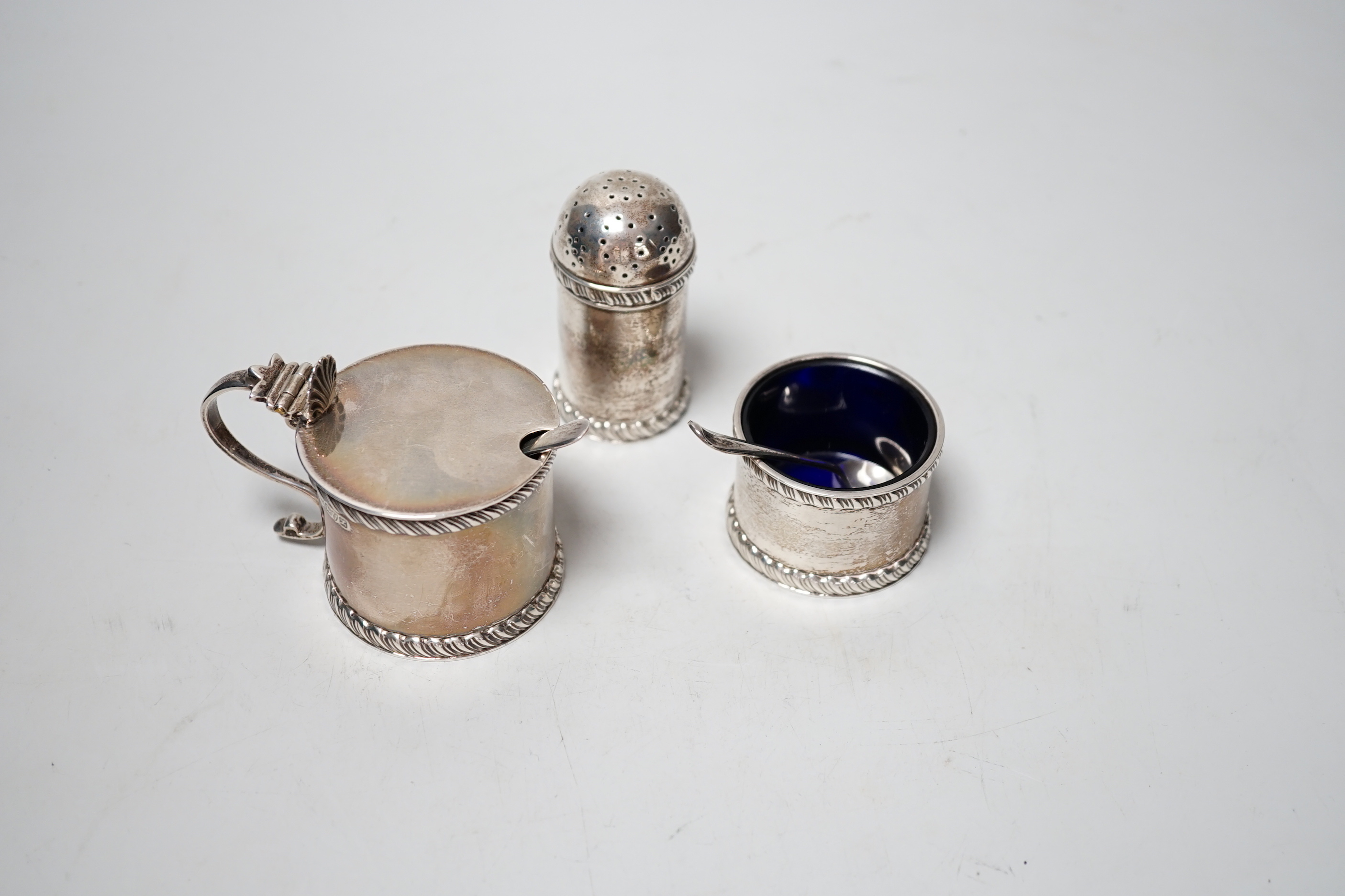 A George V three piece silver condiment set, Stokes & Ireland, Chester, 1923 and two associated spoons.